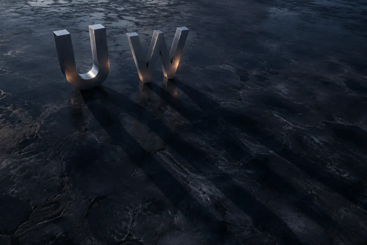 The U and W sculptures casting long shadows across an open mineral plain